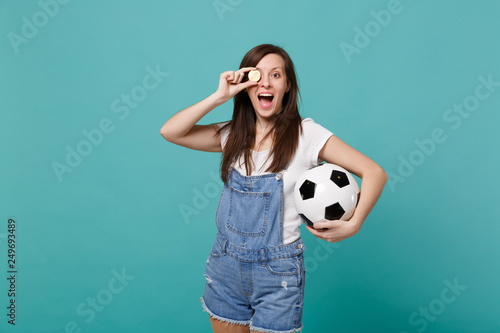 Cheerful young girl football fan support favorite team with soccer ball, covering eye with bitcoin future currency isolated on blue turquoise background. People emotions, sport family leisure concept. © ViDi Studio