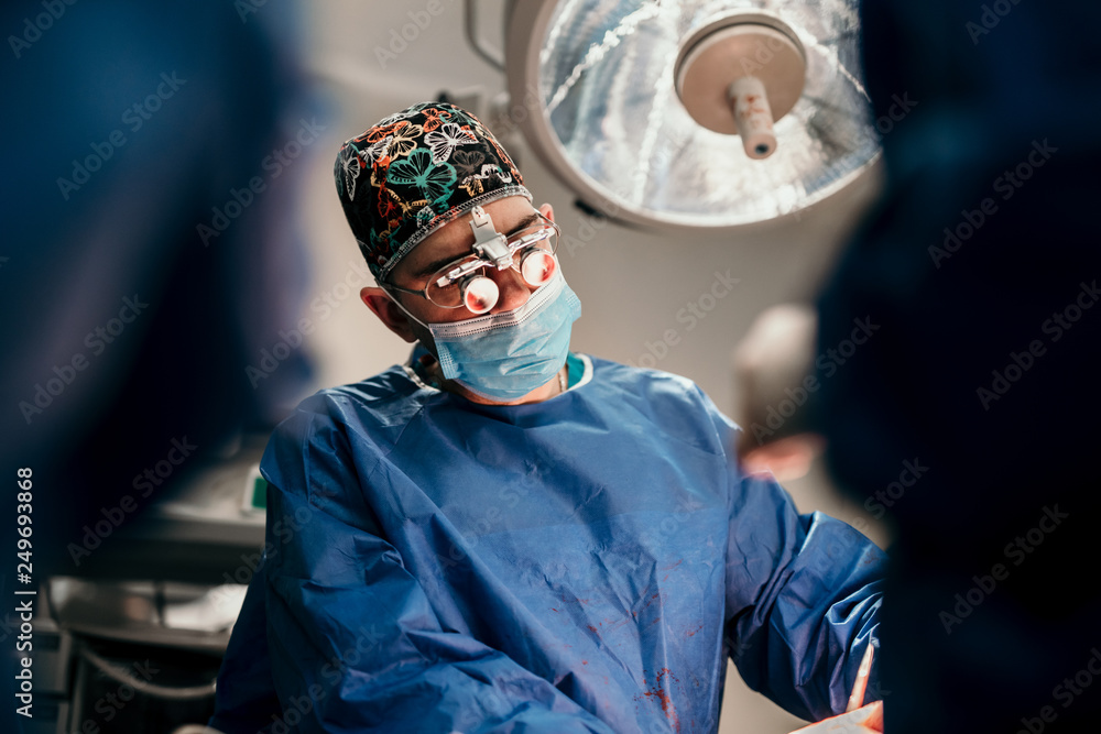 Surgeon doctor and team of doctors performing operation on live patient in sterile hospital room Surgeon doctor and team of doctors performing operation on live patient in sterile hospital room