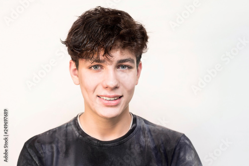 Portrait of a beautiful boy on a light background with dark hair in a dark shirt smiling