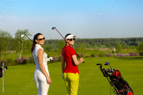 Two pretty women golfers walking and talking at golf course