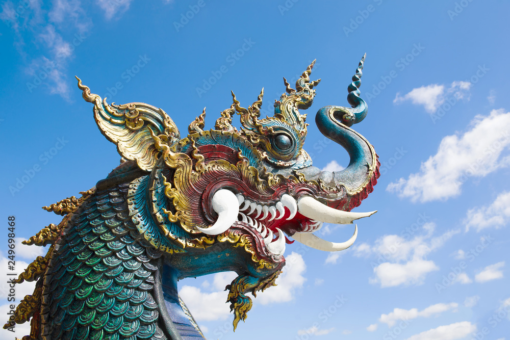 The head of a dragon against a blue sky. Buddhist temple Wat Rong Seur Ten (Blue Temple). Chiang Rai, Thailand