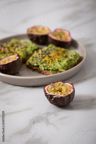 Avocado Kurkuma Vollkorn Sonnenblumenkern Brot und Maracuja zum Frühstück auf Marmor Hintergrund
