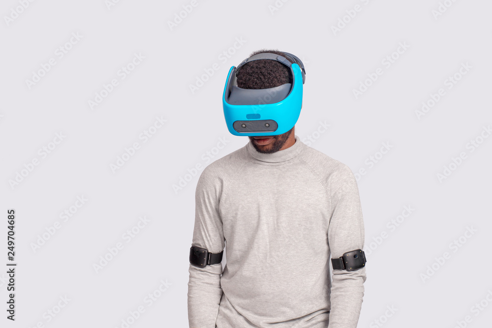 Virtual Reality headset on a black male with video game controllers over white background. Man looking down through vr glasses. Virtual Reality headset on a black male with video game controllers over white background. Man looking down through vr glasses.