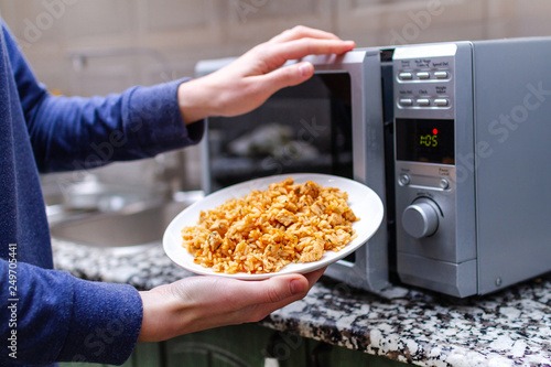 Quadro em tela Using a microwave to warming a plate of homemade pilaf for lunch at home