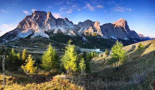 Gorgeous sunny view of Dolomite Alps with yellow larch trees. Colorful autumn scene of Tofana di rozes mountain range. Falzarego pass location, Italy, Europe. Beauty of nature concept background