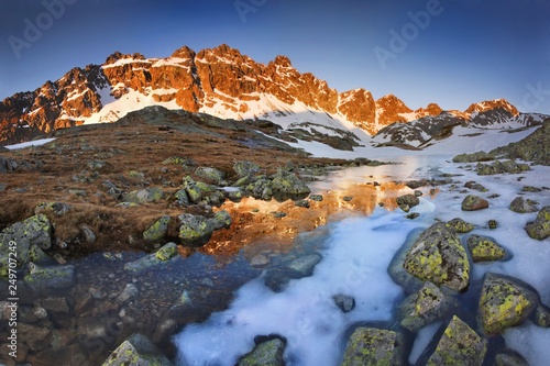 Spring or summer morning by lake in mountains. Morning beautiful nature scene. High Tatras mountain lake at reflection in water, Carpathians, Slovakia. Beautiful morning background