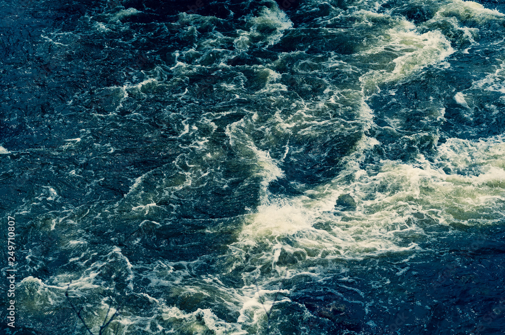 Background, top view, rapid flow of the river with dark blue water and white foam waves