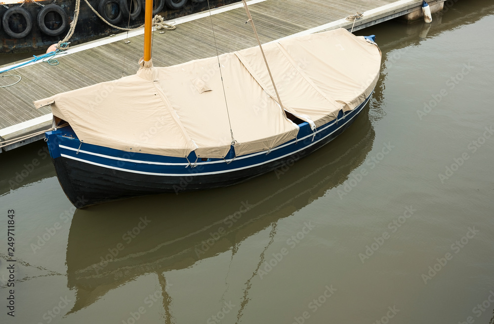 Small boat moored and covered up in harbour