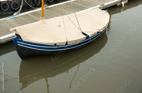 Small boat moored and covered up in harbour © simonXT2