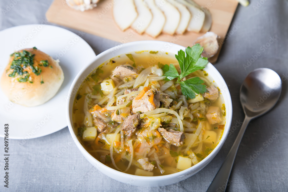 Shchi (cabbage soup) with buns (pampushki), fat and garlic. Traditional Russian and Ukrainian soup. Selective focus, close-up. Shchi (cabbage soup) with buns (pampushki), fat and garlic. Traditional Russian and Ukrainian soup. Selective focus, close-up.
