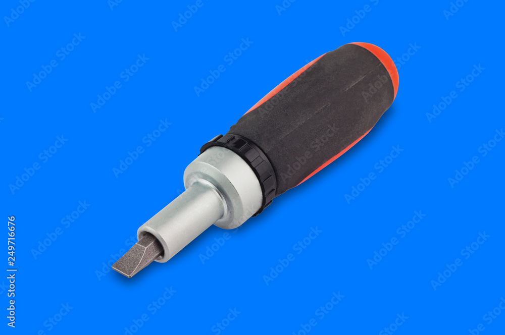 Fototapeta premium One ratchet screwdriver with orange and black plastic with rubber handle and bit in center on blue background