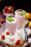 Refreshing milkshakes and bowl with fresh strawberry on wooden table