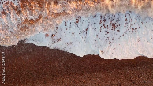 Winters Surf : Aerial image depicting two adventurers braving the freezing cold sea waters off a pebble beach. As the waves roll in, the sun low in the sky paints the foaming surf in shades of gold.