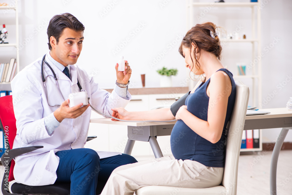 Young doctor checking pregnant woman's blood pressure Young doctor checking pregnant woman's blood pressure