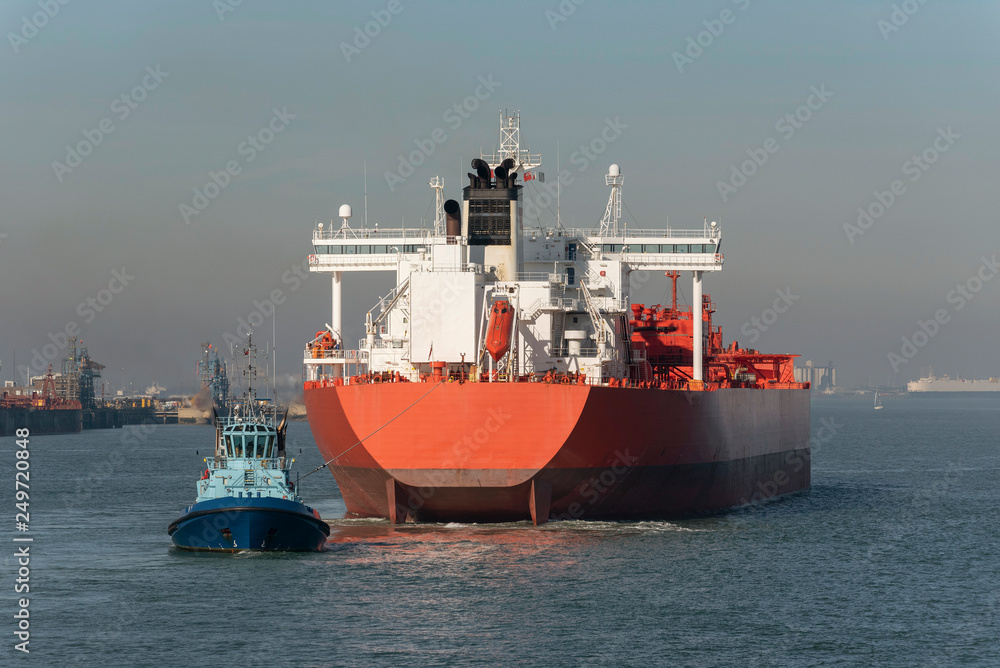 Tug with a stern line attached manouvering a crude oil tanker ship onto a berth at a refinery Tug with a stern line attached manouvering a crude oil tanker ship onto a berth at a refinery