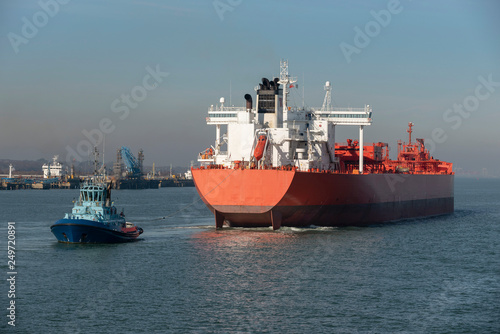 Tug with a stern line attached manouvering a crude oil tanker ship onto a berth at a refinery