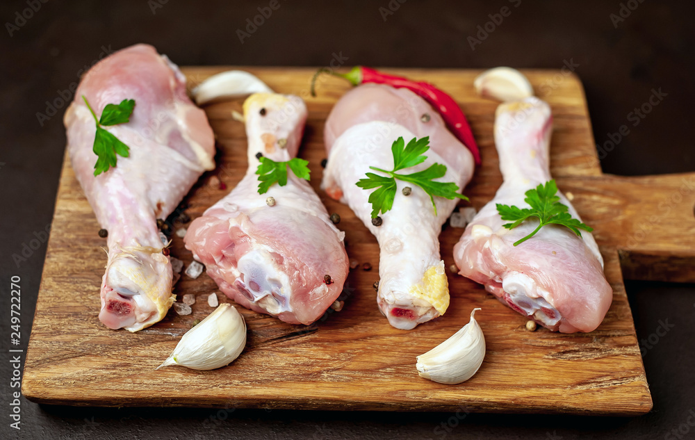 Chicken legs with spices, ready for cooking on a cutting board, background concrete