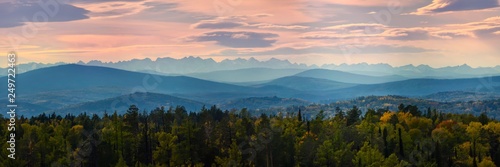 Wide angle panorama autumn forest,misty hills mountain tops in pink dawn