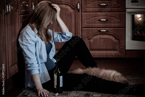 Slika na platnu Woman have a depression, problem with alcohol, she sit in a floor in kitchen wit