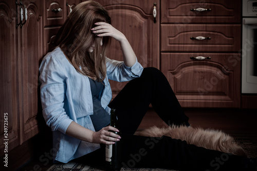 Woman have a depression, problem with alcohol, she sit in a floor in kitchen with a dog 