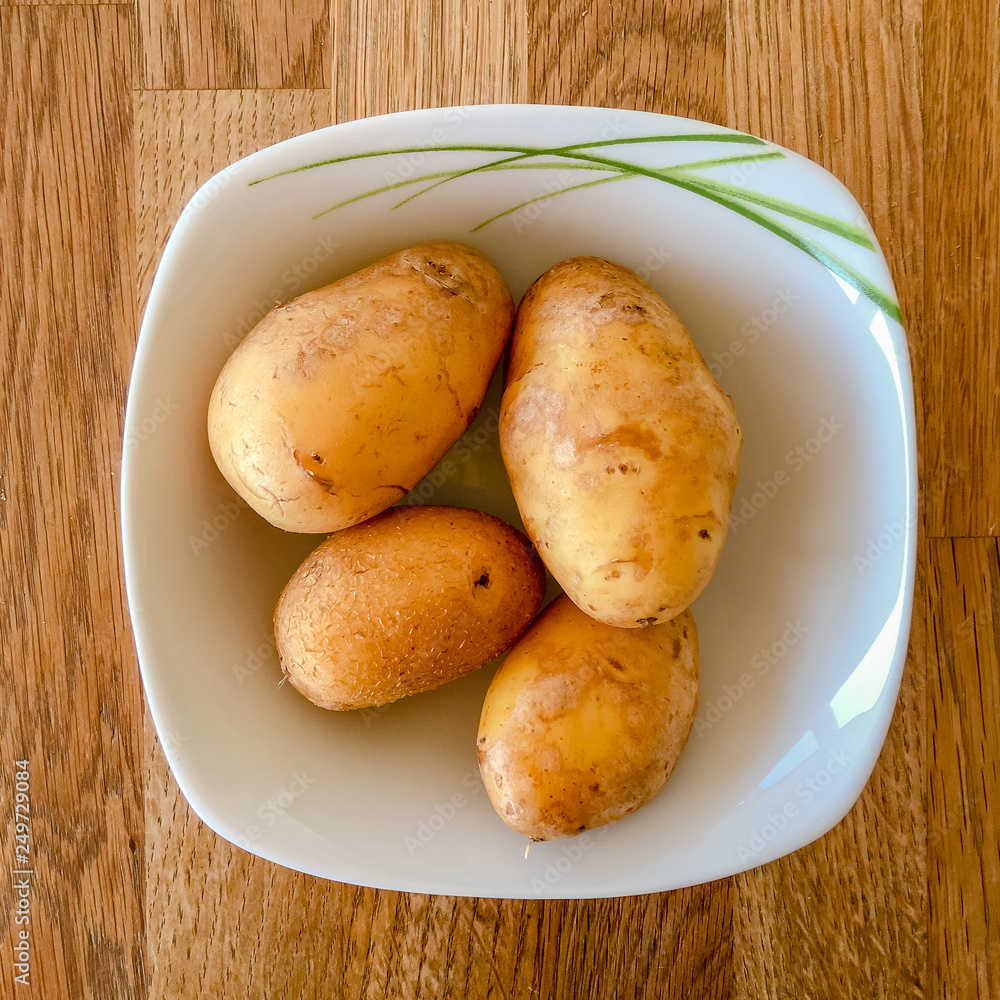 Four ptatoes in a whhite bowl Four ptatoes in a whhite bowl