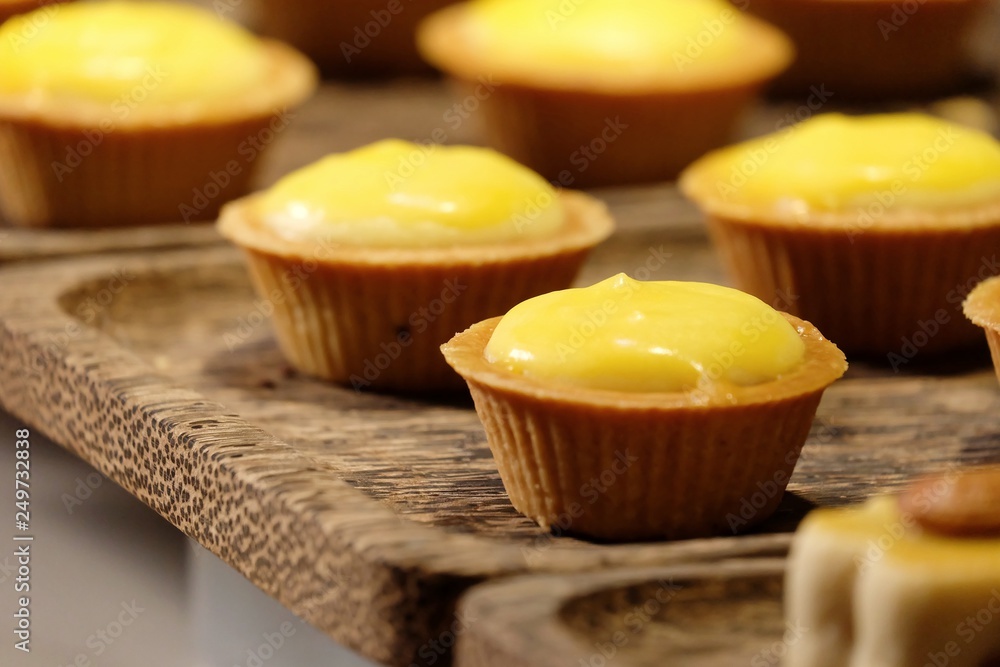 In selective focus of a row cheese tartlets on wooden tray and selling in the whole foods market In selective focus of a row cheese tartlets on wooden tray and selling in the whole foods market
