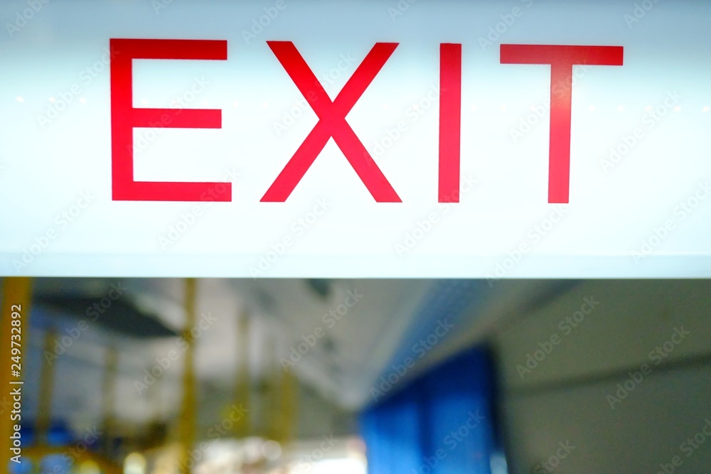 A white signpost of the word EXIT on white board hanging inside the public bus in Thailand 