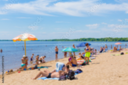Abstract blurred image. Defocused lens, bokeh. People sunbathe and swim in the river on a sandy beach. On a Sunny summer day. © Andrey Lapshin