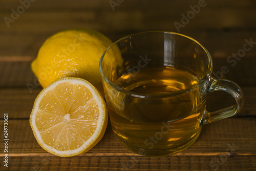 Glass Cup and lemons with tea on wooden table. Prevention of colds. Healthy diet.
