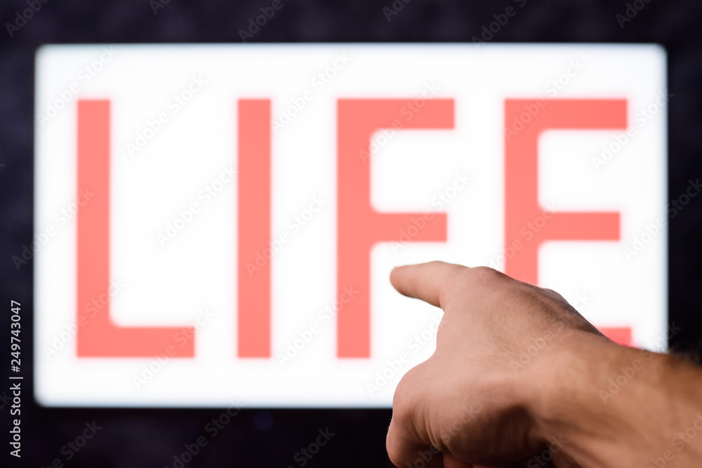 Man pointing to a TV with inscription LIFE Man pointing to a TV with inscription LIFE