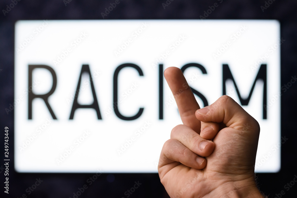 Say no to racism. Caucasian male showing middle finger to inscription RACISM Say no to racism. Caucasian male showing middle finger to inscription RACISM