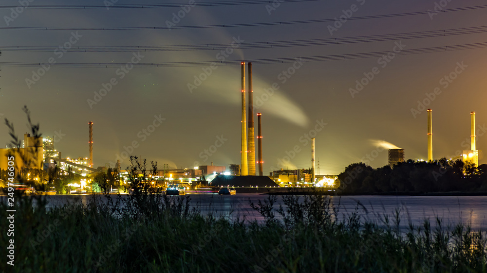 Kamine und Industrie in der Nacht am Rhein in Duisburg