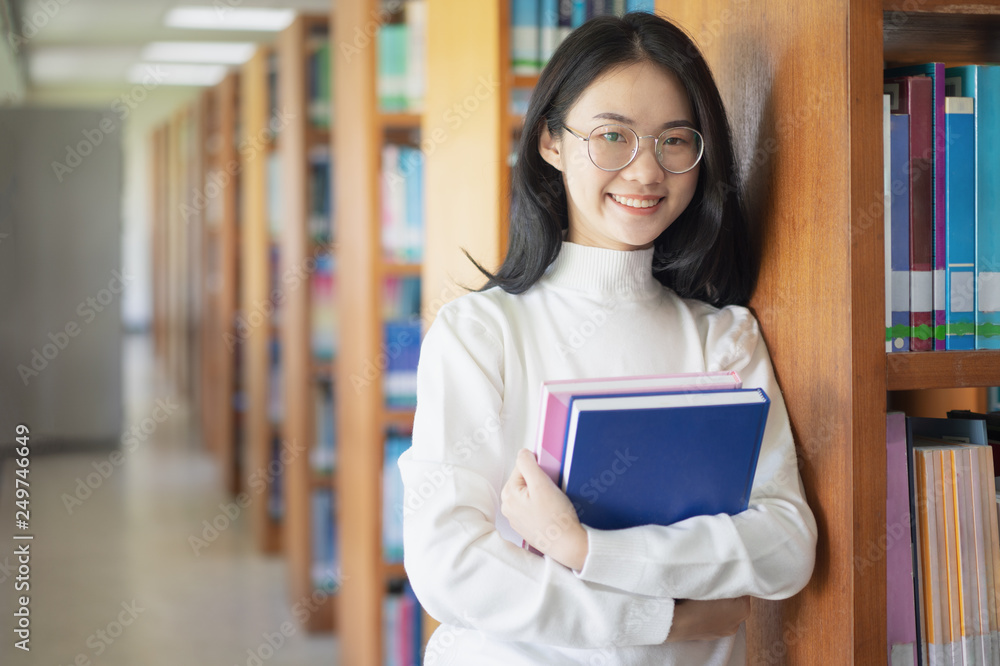 Back to school education knowledge college university concept, Beautiful female college student holding her books smiling happily standing in library, Learning and education concept Back to school education knowledge college university concept, Beautiful female college student holding her books smiling happily standing in library, Learning and education concept