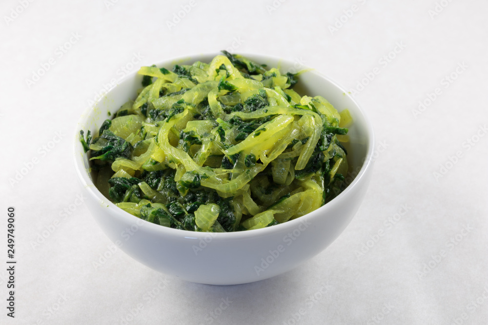 Stir fried spinach and onion. Concept of vegan food or garnish at least. White background. Stir fried spinach and onion. Concept of vegan food or garnish at least. White background.