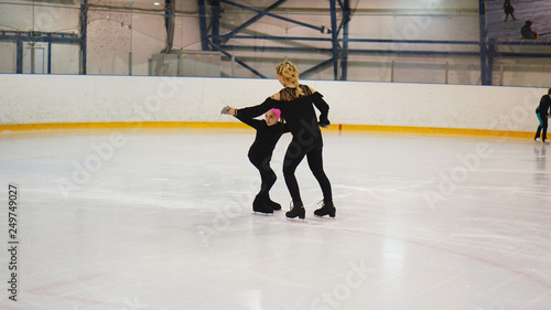 Female coach in figure skating training little girl at indoor rink