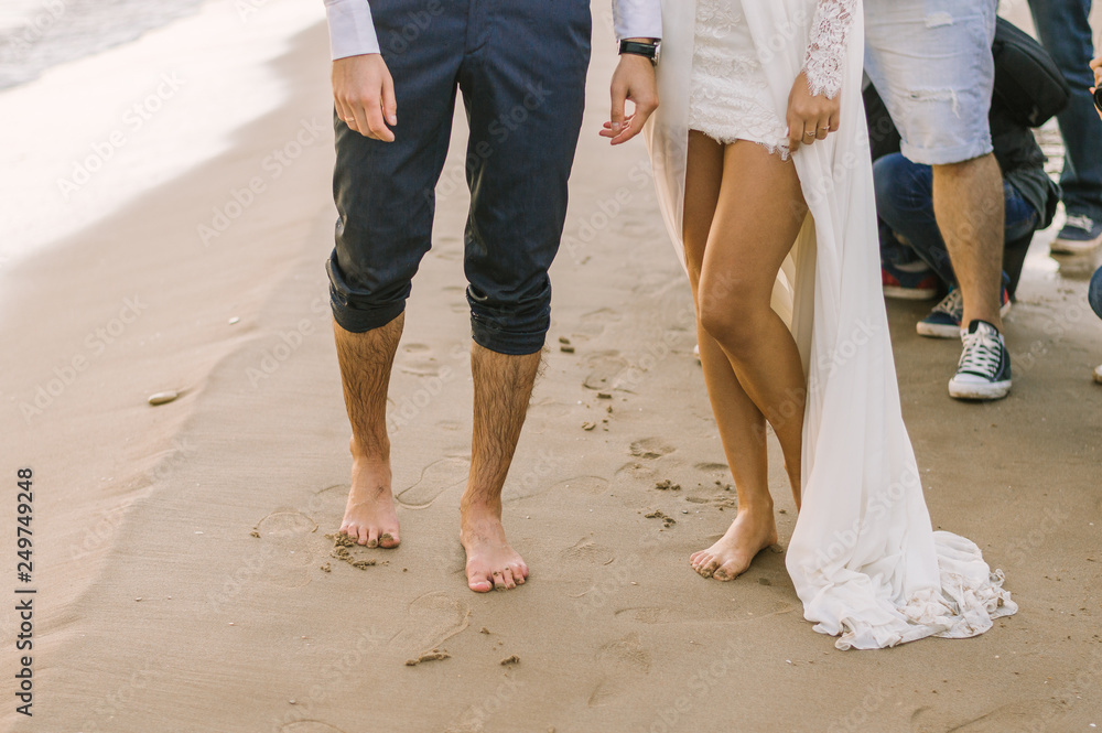 Wedding. Bare feet of loving men and women on a sandy beach by the sea.