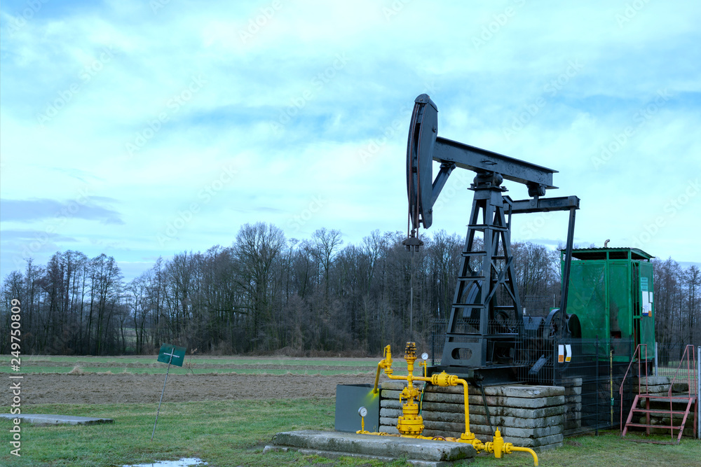 an oil pump pumps oil in the middle of a field. an oil pump pumps oil in the middle of a field.