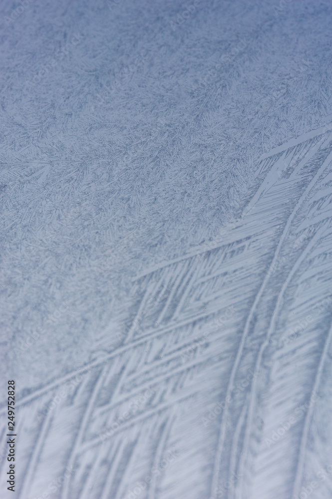 Fototapeta premium Close up of abstract patterns of ice forming on a frozen windshield