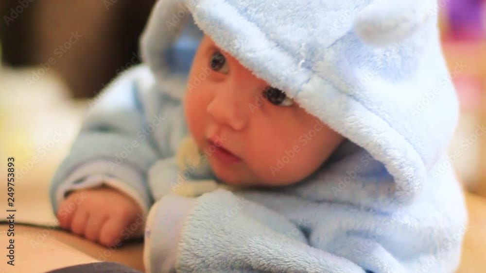 Smiling little baby girl with big blue eyes lying on her tummy on white bed looking at camera and smiling Smiling little baby girl with big blue eyes lying on her tummy on white bed looking at camera and smiling