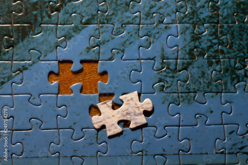 put the last piece of jigsaw puzzle to complete the mission on wood background