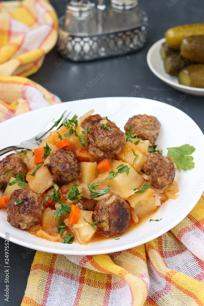 Stewed potatoes with meatballs on a white plate