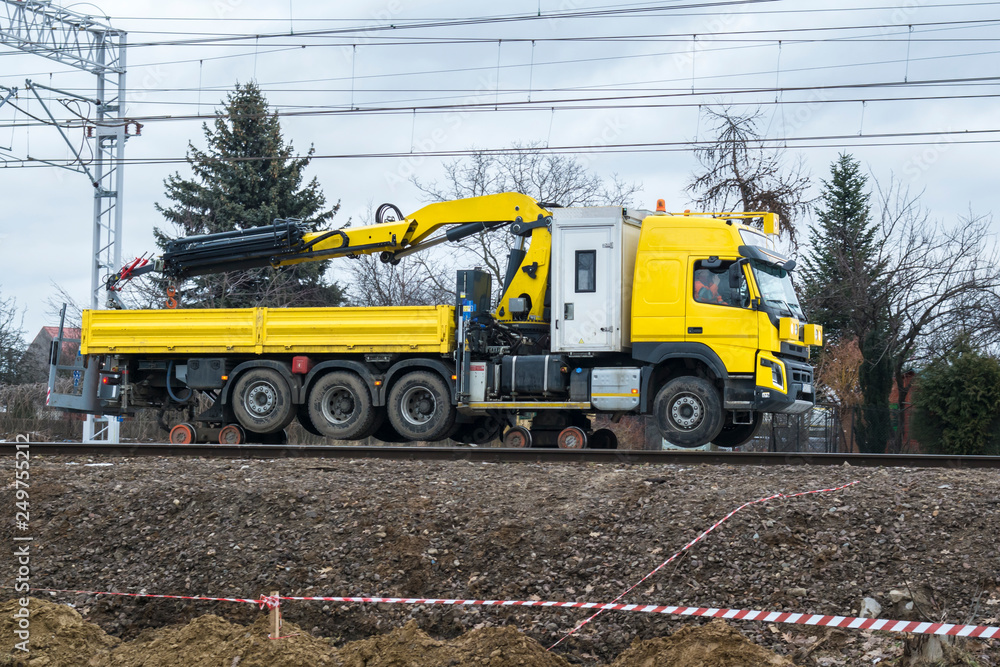 Yellow machine crane servicing repair of railway tracks rides on rails