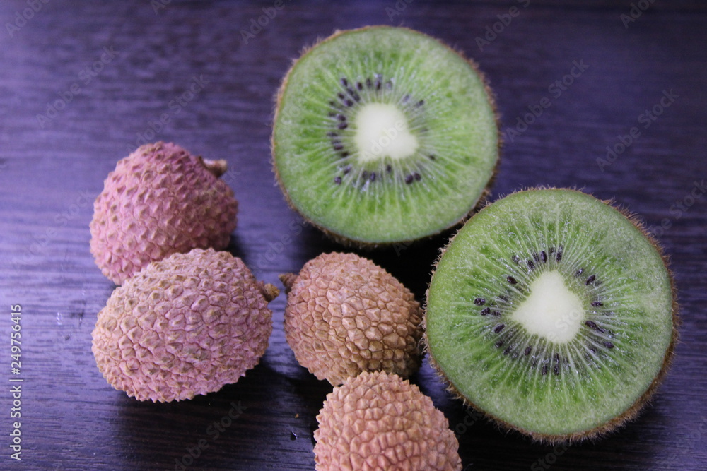 juicy kiwi in the cut and Litchi chinensis on a dark background