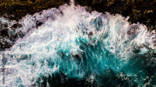 Aerial top vertical view of big waves at the beach - power of the ocean and dangerous nature - colors and texture foam background - beautiful coast landscape