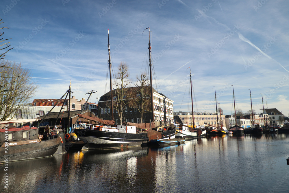 old museum harbor of Gouda with historic ships at mallegatsluis sluice to the Hollandsche IJssel in the Netherlands