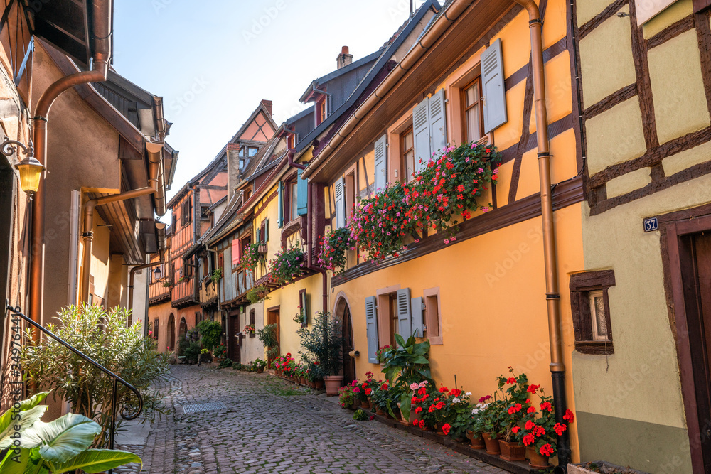 Cobblestone street in picturesque Alsace village with half timbered houses and beautiful flowers. 
