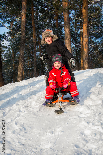 In winter, children ride a snow scooter from a hill.