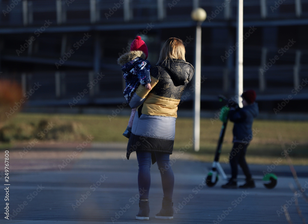a woman with a child in her arms and a second child on a scooter, Poland, stay at home, covid-19