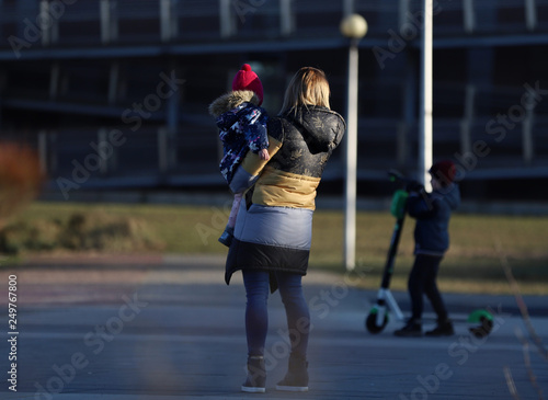 a woman with a child in her arms and a second child on a scooter, Poland, stay at home, covid-19