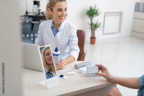 Smiling ophthalmologist in white lab coat prescribing contact lenses for patient photo